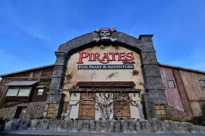 Front view of Pirates Voyage dinner show building in Pigeon Forge with pirate-themed facade and red logo under blue sky.