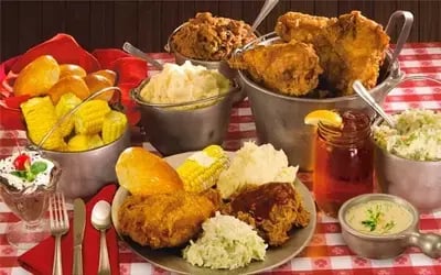 Homestyle feast at Hatfield & McCoy Dinner Feud with fried chicken, corn, mashed potatoes, ribs and coleslaw on gingham table